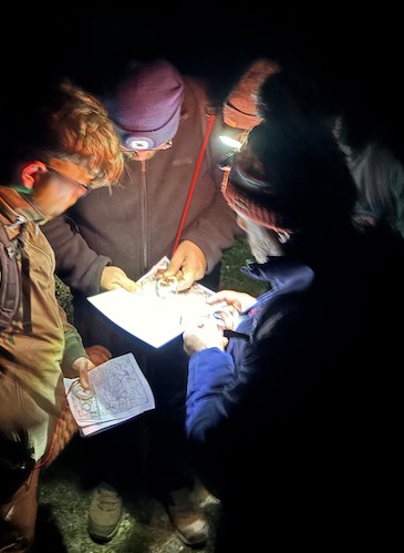 A group of hikers reading a map in darkness